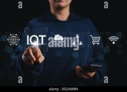 Internet of Things (IoT) concept. Person touching IoT icon with elements of cloud computing, connectivity, e-commerce, and wireless networks, symboliz Stock Photo