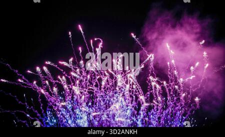 Vibrant Purple and Blue Fireworks Exploding Against Night Sky Stock Photo