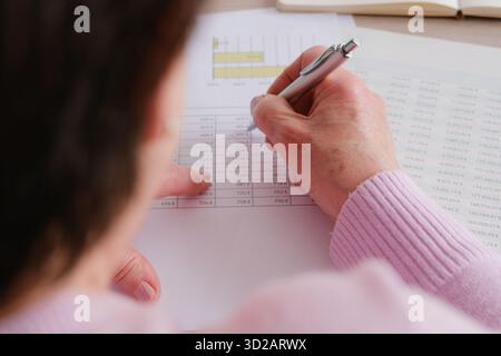 Over the shoulder view of a businesswoman analyzing financial documents and data Stock Photo