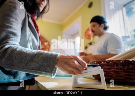 Woman paying via tap to pay method with credit card while shopping at home decor shop Stock Photo