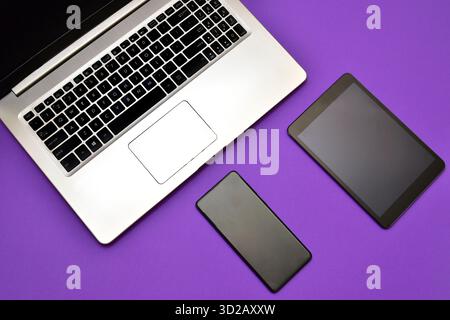 A modern workspace featuring a laptop, smartphone, and a tablet A classic landline telephone Stock Photo