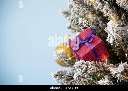 Christmas tree decorations on snowy pine on blue background. Stock Photo