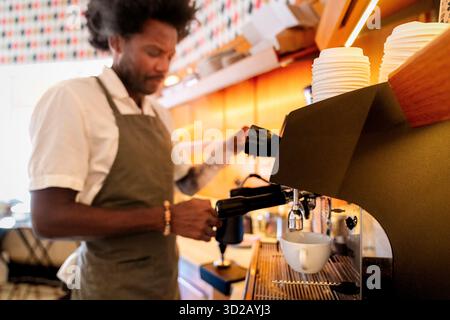 Coffee maker machine with barista working in background at cafe Stock Photo