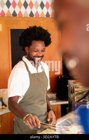 Happy male barista holding tongs while working at cafe Stock Photo
