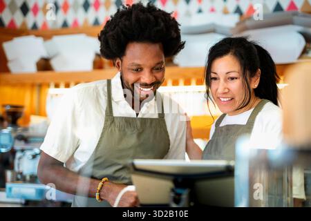 Smiling male and female baristas in apron working at coffee shop Stock Photo