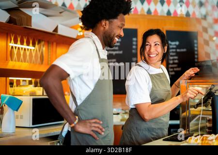 Happy female barista using digital tablet standing next to male colleague at coffee shop Stock Photo