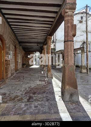Traditional portico with stone floor and wooden ceiling in old village street Stock Photo