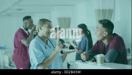 Smiling nurse in scrubs holding cake slice on plate in hospital staff lounge, with coffee cup Stock Photo