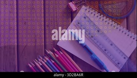 Displaying spiral-bound notebook on wooden desk at workspace with ruler, blue pen, colored pencils Stock Photo