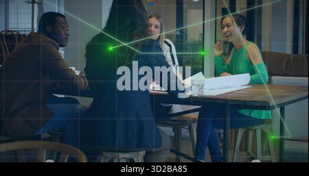 Discussing four professionals reviewing blueprints on table in meeting room, with glass of water Stock Photo