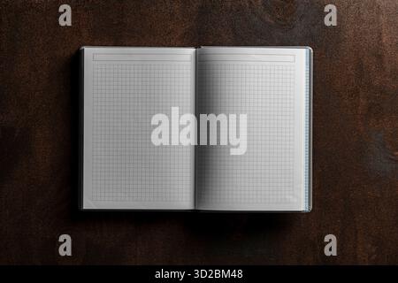 Open notebook with checkered sheets on wooden texture background, close up, top view, copy space Stock Photo