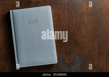 2026 gray notebook on wooden texture background, close up, top view, copy space. Calendar planner, organizer, business event schedule concept Stock Photo