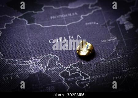 A gleaming gold dental crown shines in the foreground, set against a map of China—symbolizing the nation’s powerful role in global gold mining, produc Stock Photo