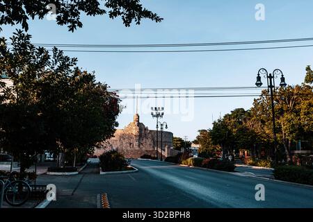 Merida, Yucatan, Mexico, Street with a building in the background and a few trees. The street is empty and the sky is blue Stock Photo