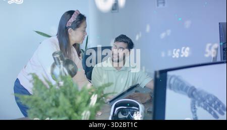Collaborating team sketching robotic arm design on digital tablet at office desk near VR headset Stock Photo
