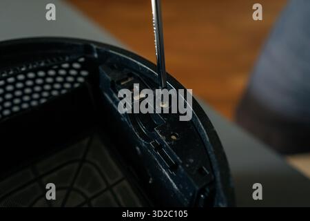 Close-up hands of unrecognizable technician using screwdriver to repair or maintain air humidifier, emphasizing importance of regular maintenance for Stock Photo