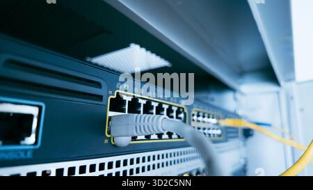 Gray ethernet cable connected to professional switch in server cabinet, symbolizing network management, cybersecurity, and stable digital data infrast Stock Photo