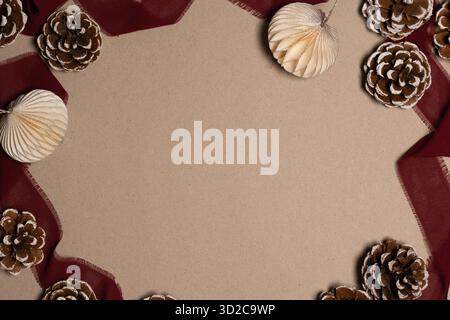 Blank mockup copy space with pine cones, red ribbon and paper baubles on a neutral beige background. Christmas minimalistic aesthetic template. Stock Photo