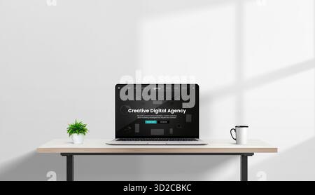 Laptop on minimalist desk with plant and coffee mug displaying creative digital agency website in dark mode, modern bright office with soft shadows Stock Photo