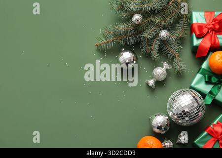 Composition with disco balls, gift boxes, tangerines and Christmas decor on green background Stock Photo