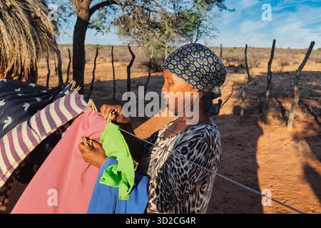 village african woman, putting wet clothes on a washing line in the yard, homework chores washing laundry Stock Photo