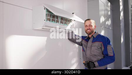 Skilled Technician Fixing Air Conditioning Unit In Happy Man's House. Stock Photo