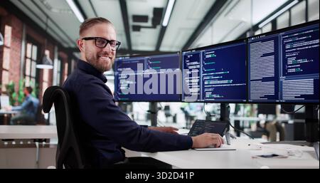The Happy Coder: Man Thriving In Tech With Multiple Screens. Stock Photo