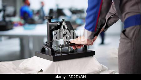 Young Man Designs Custom T-shirt Graphics Using Digital Printing Machine. Stock Photo