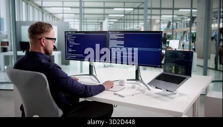 Young Male Programmer Debugging Code On Office Desktop Computer Station. Stock Photo