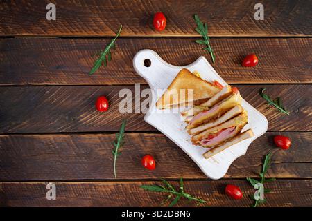 Club sandwich with ham, tomatoes, cheese and herbs. Toasts with filling Stock Photo