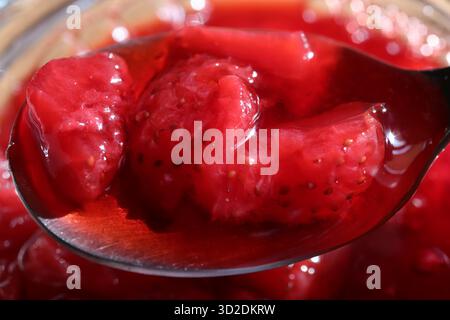 Pieces of strawberry jam on a spoon. Sweet juicy background. Macro closeup. Stock Photo