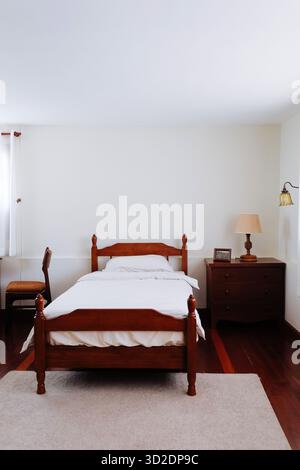image of Wooden bed and furniture in a hotel room with white sheets and pillows, vintage bed room decor Stock Photo