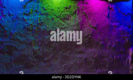 Rough plaster wall with heavy texture under colorful neon lights, moody gradient hues of blue, green and magenta creating vivid abstract backdrop Stock Photo