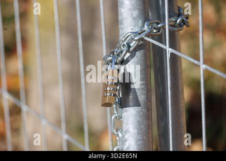 Chain is attached to a metal fence post with a lock on it Stock Photo