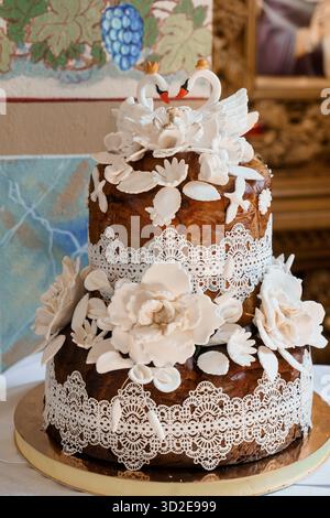 A beautifully crafted two-tier wedding cake adorned with white fondant swans, intricate lace patterns, and delicate floral decorations, set against a Stock Photo