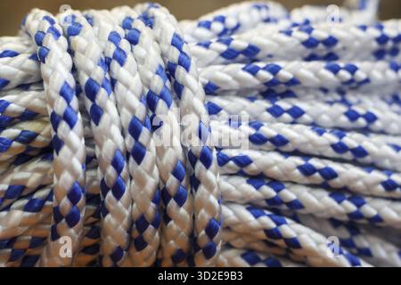 Detailed macro photography of strong white and blue braided rope coil. intricate texture and repeating pattern show strength, creating background of o Stock Photo