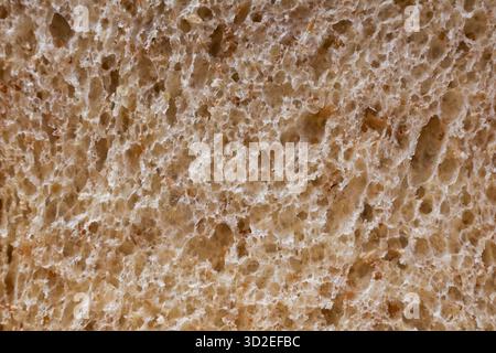 Comforting macro close up of brown bread slice food texture. This whole wheat porous background reveals intricate detail of crumb for rustic, wholesom Stock Photo