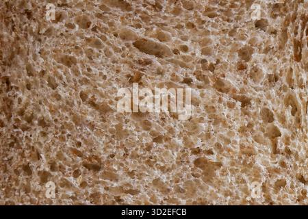Wholesome macro background of brown bread texture, detailed close up of baked slice. This natural, rustic food provides perfect organic, culinary wall Stock Photo