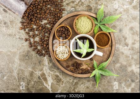 Coffee beans, a cup of freshly brewed coffee with cannabis, morijuana seeds and leaves on a tray. top view Stock Photo