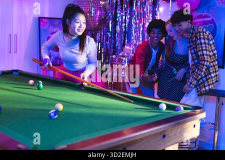 Teenagers playing pool at birthday party, enjoying celebration with friends. Teens, billiards, friendship, leisure, fun, recreation || Model released Stock Photo
