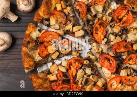 Wood-fired pizza topped with grilled chicken, mushrooms, and sliced tomatoes on a golden crust. Stock Photo