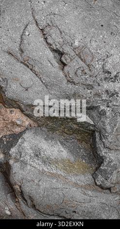 Close-up of an old concrete wall with deep cracks and worn cement revealing reddish brick beneath. Stock Photo