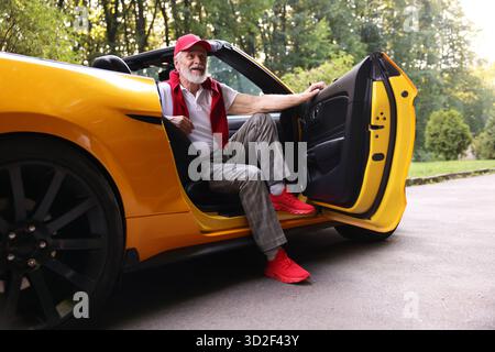 Stylish senior man getting out of modern cabriolet outdoors Stock Photo
