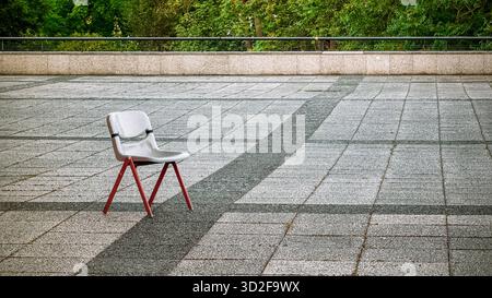 Single red-legged chair on a concrete plaza in Berlin creating a minimalist geometric scene Stock Photo