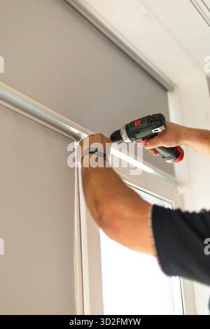 Process of installing window blinds using screwdriver and tools indoors. Stock Photo