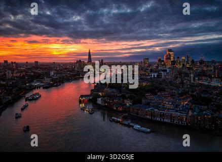 Aerial view of the urban skyline of London, England, with river Thames leading into the City during a colourful sunset Stock Photo
