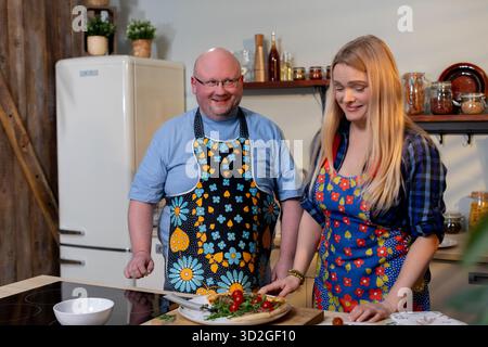Pair preparing food collaboratively indoors, Man and woman cooking side by side, Two individuals collaborating on recipe with vibrant produce in Stock Photo