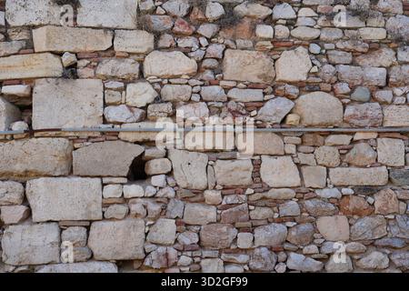 Close-up of an ancient stone wall in Athens, Greece, showing rough texture, mixed masonry, and historic construction details. Stock Photo