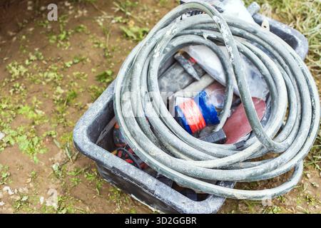 Coiled gray hose placed inside a plastic box with various construction tools and equipment. Concept of renovation, building materials, and repair work Stock Photo