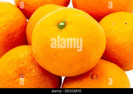 A macro shot of a pile of bright, ripe mandarins. The close-up of the peel shows its texture and bright orange color. Stock Photo